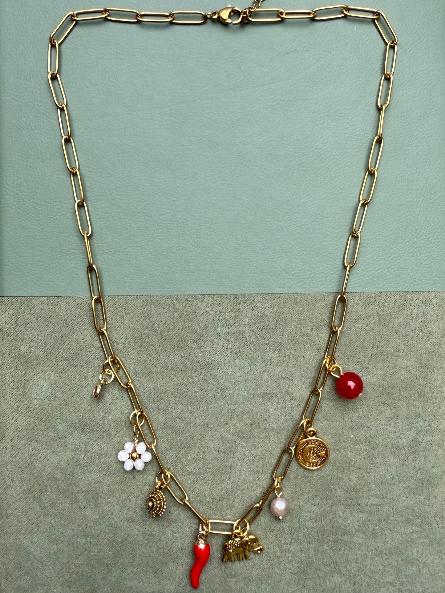 Gold chain necklace with charms on a green background