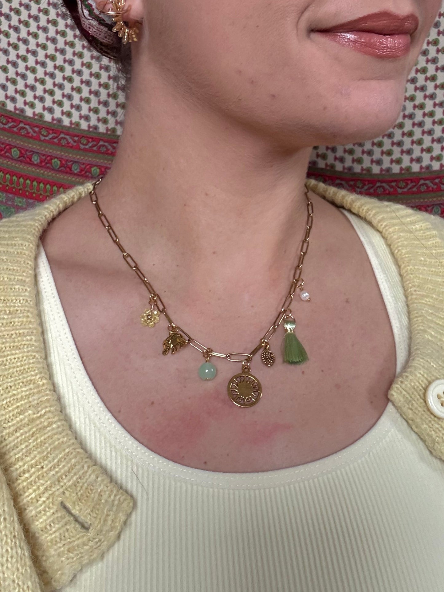 Person wearing a necklace with a pendant, lying on a patterned surface.