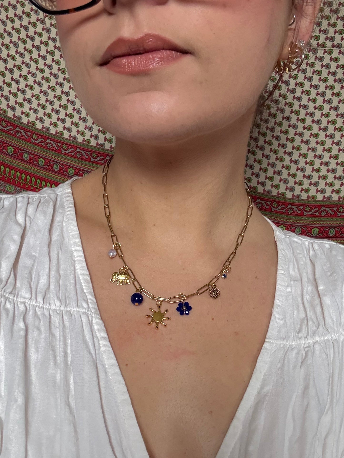 Person wearing a gold necklace with beads on a patterned surface