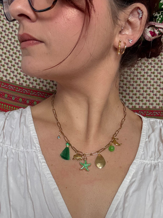 Person wearing a gold necklace with charms on a patterned surface